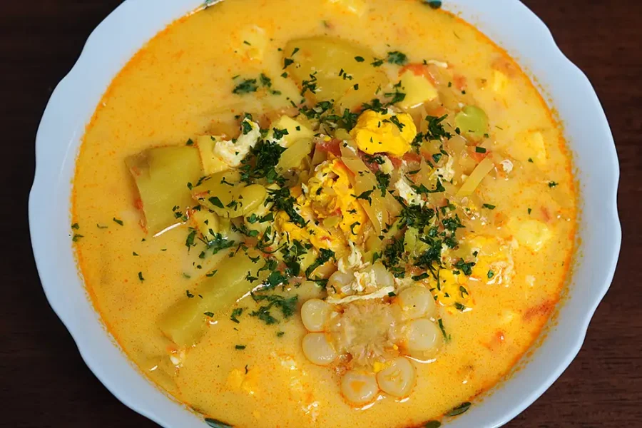 Chupe de Ollucos peruano en tazón de barro, con ollucos, papas, choclo y huevo. Sopa andina tradicional.