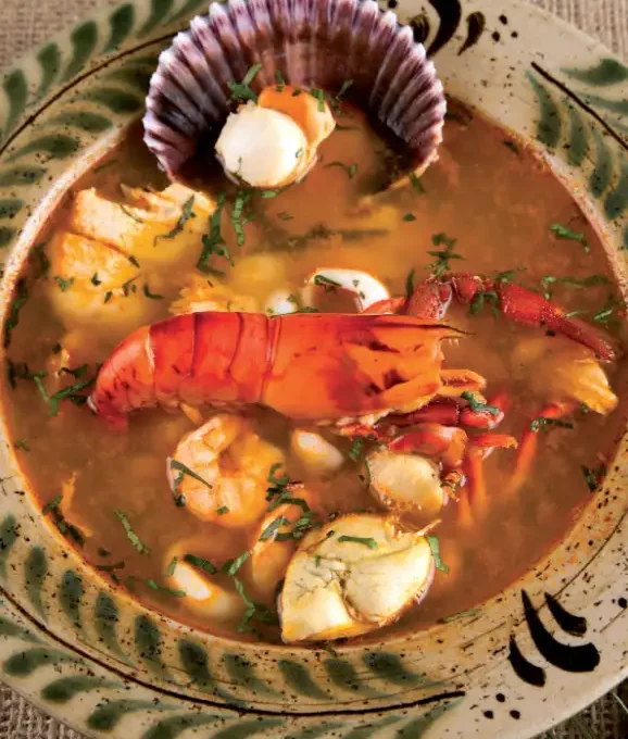 Parihuela peruana con mariscos frescos en tazón rústico. Sopa tradicional de la costa del Perú.