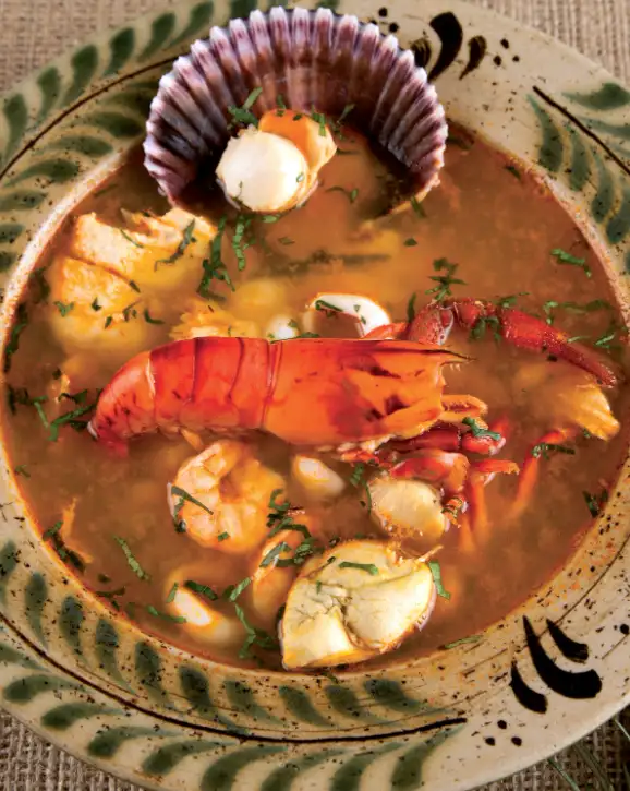 Parihuela peruana con mariscos frescos en tazón rústico. Sopa tradicional de la costa del Perú.