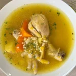 Plato hondo de sopa de pollo con fideos receta peruana, con zapallo, papa amarilla, zanahoria, apio y culantro fresco espolvoreado, servido caliente.
