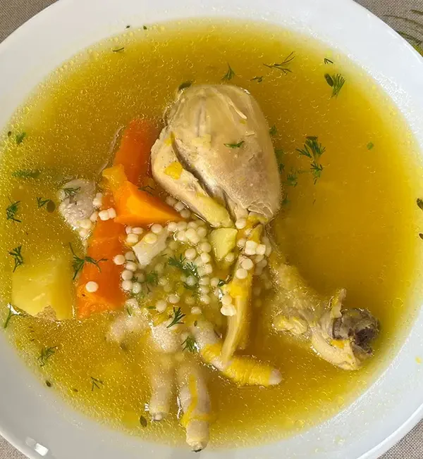Plato hondo de sopa de pollo con fideos receta peruana, con zapallo, papa amarilla, zanahoria, apio y culantro fresco espolvoreado, servido caliente.