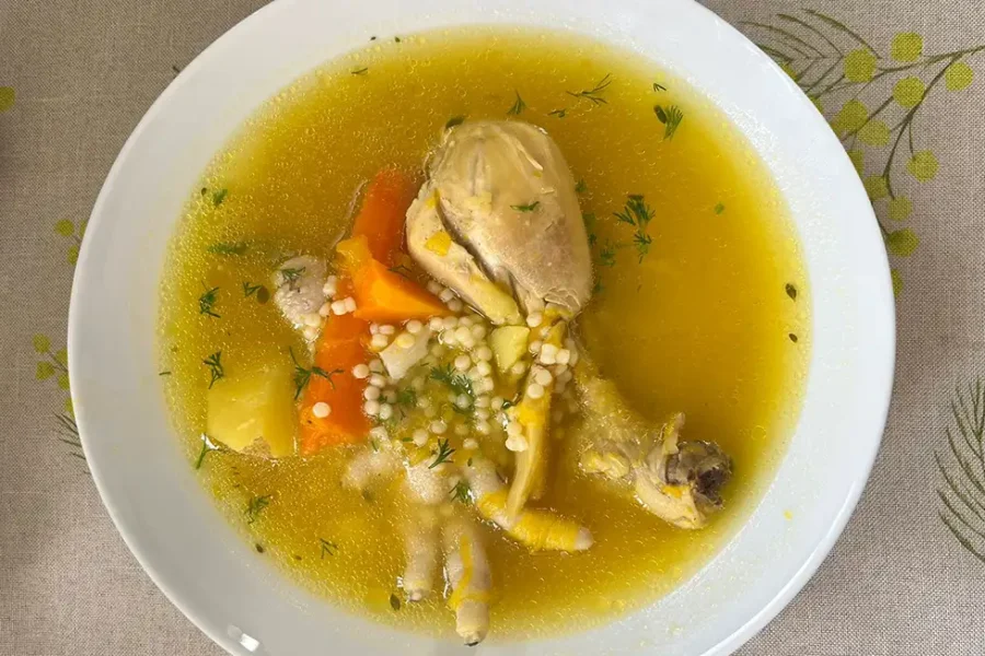 Plato hondo de sopa de pollo con fideos receta peruana, con zapallo, papa amarilla, zanahoria, apio y culantro fresco espolvoreado, servido caliente.