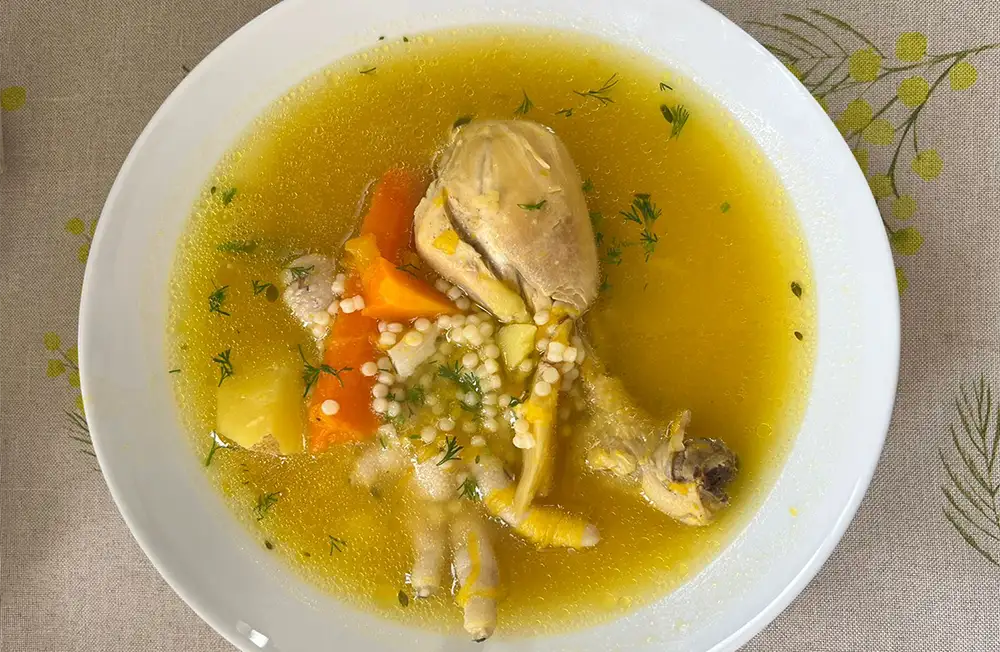Plato hondo de sopa de pollo con fideos receta peruana, con zapallo, papa amarilla, zanahoria, apio y culantro fresco espolvoreado, servido caliente.