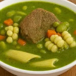 Sopa Menestrón peruano en un tazón rústico con ingredientes tradicionales como carne, choclo, menestras y pesto verde