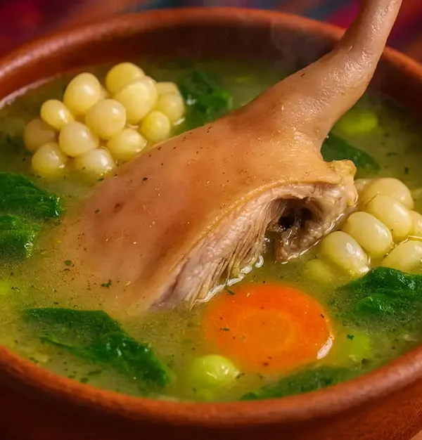 Sopa tradicional peruana de caldo de cuy con quinua, verduras frescas y especias, servida en un bowl